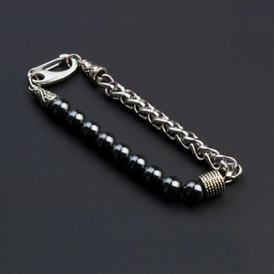 Macro view of men's punk bracelet featuring black beads and a chunky silver metal chain
