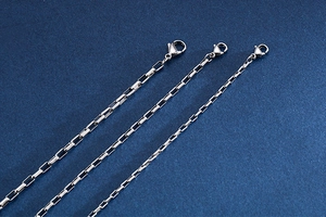 Detailed close-up of three silver rectangle link chains with lobster clasp closures