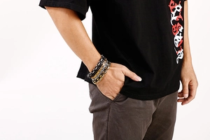 Close-up of a three-tone king chain bracelet in black, silver, and gold on a male wrist