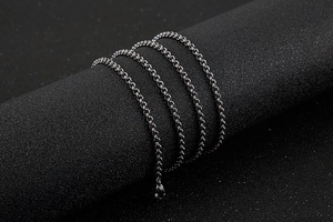 Macro detail of silver stainless steel O-chain links on a black textured display pedestal