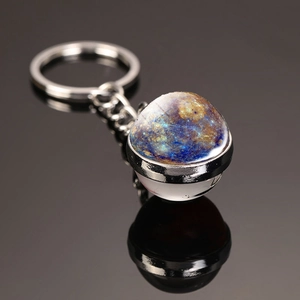 Macro shot of double-sided glass moon keychain with nebula galaxy pattern on black surface