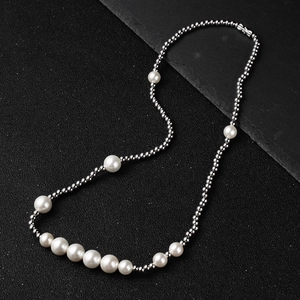 Detail view of pearl and silver bead necklace on black stone background