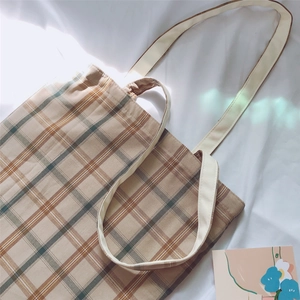 Detail shot of vintage beige checkered canvas tote bag on soft white fabric background