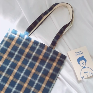 Detail of classic plaid canvas tote bag with navy and orange check pattern on white fabric