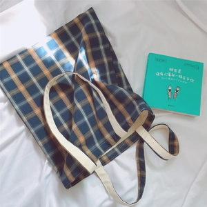 Close-up of checkered canvas tote bag with thick white woven handles and plaid texture