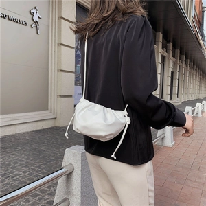 Detail of white pleated dumpling bag showing matte leather texture and soft cloud shape