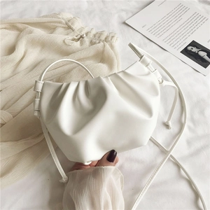 Detailed close-up of white pleated cloud bag made of soft PU leather on fabric