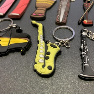 Detail view of colorful PVC musical instrument keychains including saxophone and piano