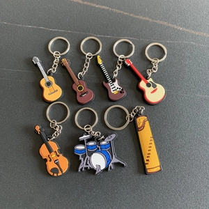 Detailed view of various musical instrument PVC keychains including guitar and violin