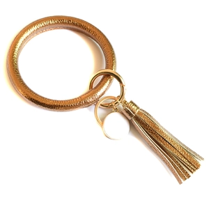 Detailed macro view of champagne gold PU leather wristlet ring with white tag and long tassel