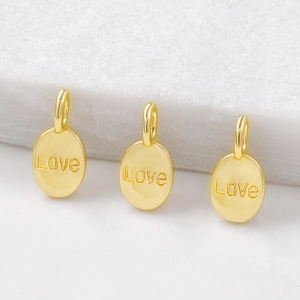 Three gold oval Love charms with rings displayed on a white textured surface