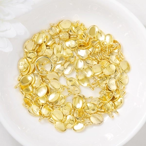 Golden oval LOVE charm pendants piled in a white bowl for DIY jewelry making