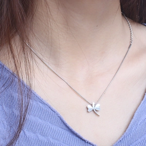 Minimalist silver four-leaf clover pendant necklace worn by a model on a snake chain