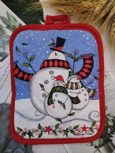 Macro view of quilted cotton Christmas trivet with snowman pattern and red trim edge