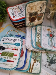 Detailed overhead view of assorted thick cotton oven pads with various floral and owl patterns