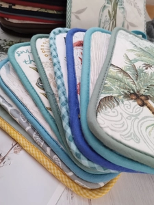 Close-up of thick cotton heat-resistant mats with various prints and hanging loops