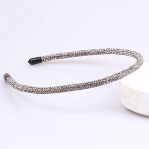 Close-up of a thin dark grey headband fully paved with shimmering micro rhinestones