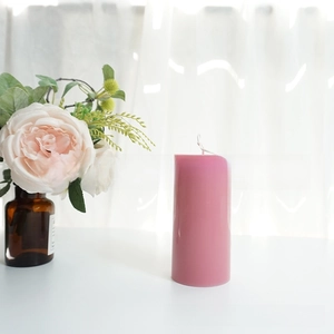Pink cylindrical pillar candle and rose bouquet detail in a cozy home setting