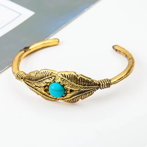 Nahaufnahme der goldenen Federstruktur und Türkisstein an einem Boho-Manschettenarmband