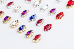 Detalle de diamantes para uñas coloridos en forma de gota y marquesa con base dorada
