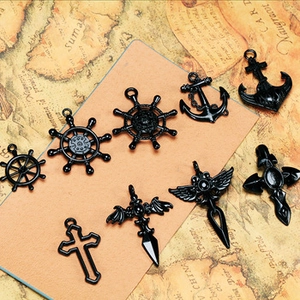 Macro shot of 9 black alloy charms featuring nautical anchors, helms and crosses