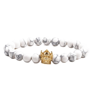 Close-up of white turquoise marble beads and a gold crown charm on a beaded bracelet