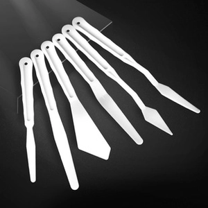 Detailed set of 6 professional white palette knives for oil and acrylic painting on dark backdrop