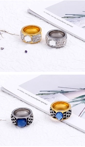 Detailed close-up of wide band rings with pavé diamonds and large center gemstones