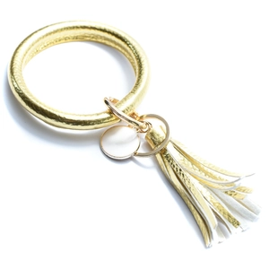 Detail of PU leather bracelet keychain with gold leaf charm and white tassel accessory