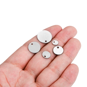 Handheld set of five silver stainless steel round blank tags in varying sizes with holes