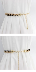 Detail of adjustable gold-tone metal and black leather woven waist chain with lobster clasp