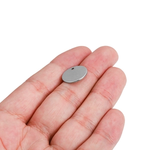 Close-up of a small silver stainless steel round pendant held in a hand for size