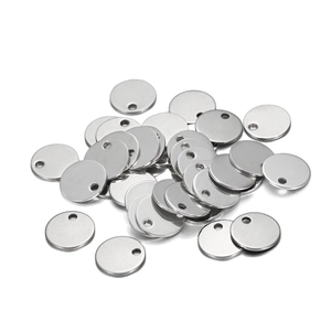 Pile of round silver stainless steel blank pendants with holes on white background