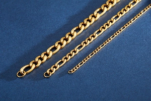 Three widths of golden Figaro style stainless steel chains on dark blue textured background