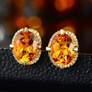 Macro shot of yellow oval gemstone stud earrings with halo diamonds in gold setting