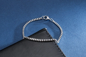 Detailed close-up of a silver titanium steel box chain bracelet with secure lobster clasp