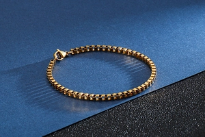 Detailed view of a gold stainless steel box chain bracelet with secure lobster clasp closure