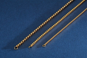 Close-up of three golden titanium steel box chains in different sizes on blue background