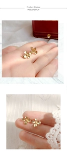 Detailed view of matte gold gardenia flower earrings held by fingers to show size