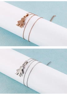 Detail of rose gold and silver boy-shaped pendants on fine link chains over a blue background