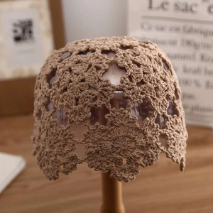 Khaki hand-woven crochet knit beanie with hollow floral patterns on a display stand