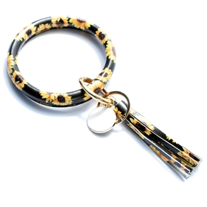 Macro detail of sunflower pattern PU leather wristlet with golden hardware and tassel