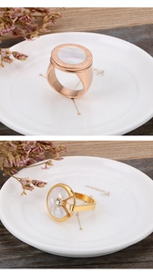 Detail of rose gold and gold shell rings with Roman numerals and crystals on wood