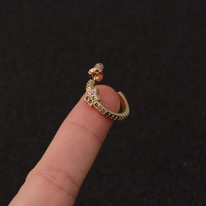 Detailed close-up of a gold C-shaped earring featuring colorful zircon-set star patterns