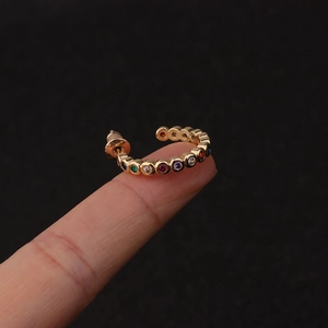 Close-up of gold hoop earrings with multi-colored crystals held on fingers