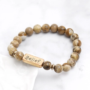 Macro shot of natural stone beaded bracelet with antique gold metal plate engraved Belief