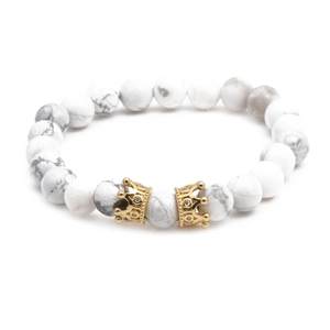 Détail macro de perles en marbre blanc et de breloques couronne dorées sur bracelet