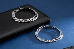 Dettaglio macro di catene a maglie Figaro e cubane in acciaio argento su pelle nera