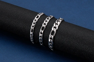 Dettaglio di tre bracciali a catena in acciaio inossidabile con maglie testurizzate chic