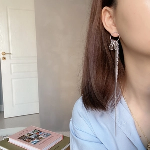 Close-up of elegant long silver tassel earrings with multiple fine chains on a model